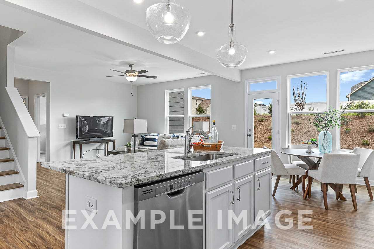 Open-concept kitchen and dining in The Willow C by Davidson Homes, with white cabinets, granite island, large windows, and hardwood floors
