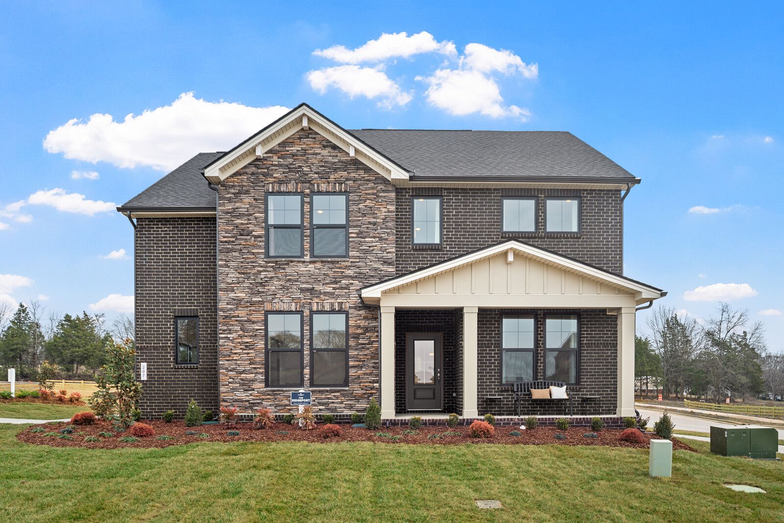 Two-story brick home exterior at Benders Cove in Mt. Juliet TN with covered front porch, gabled roof and landscaped yard