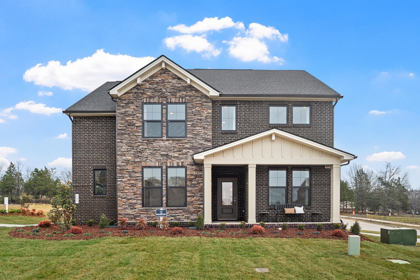 Two-story brick home exterior at Benders Cove in Mt. Juliet TN with covered front porch, gabled roof and landscaped yard