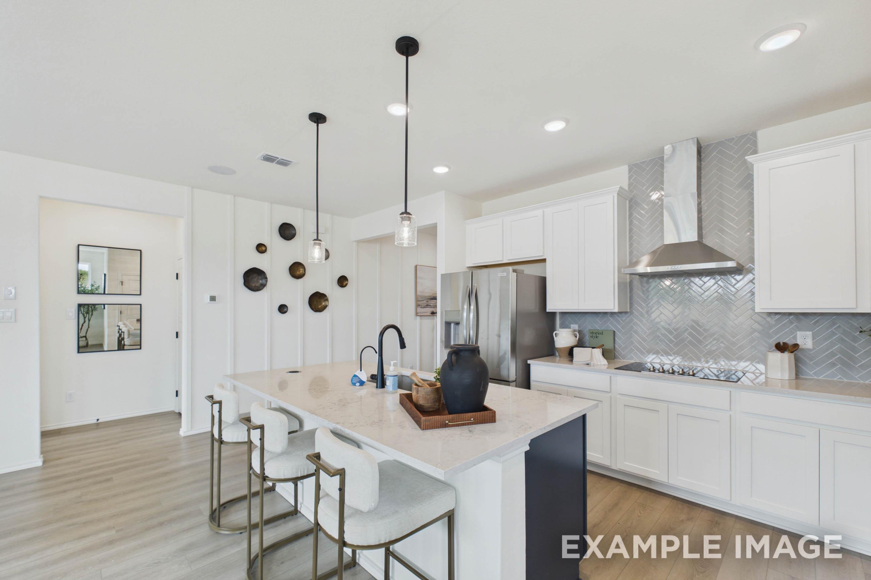 Modern kitchen in The Laurel G floor plan featuring quartz island, white cabinetry, and herringbone tile backsplash.