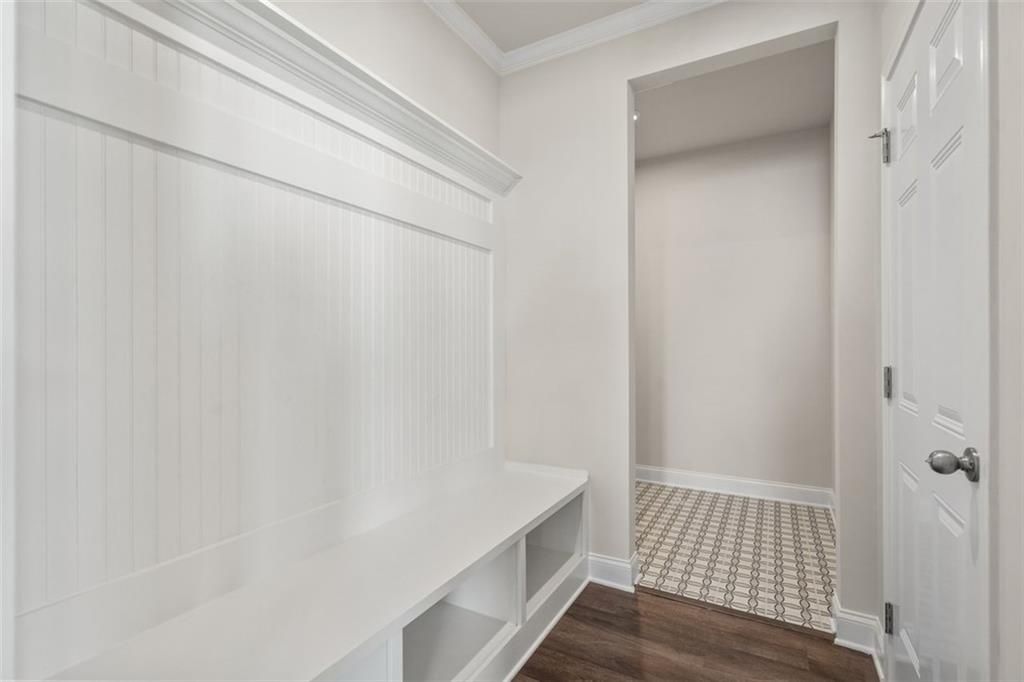 White beadboard mudroom with built-in bench, storage shelves, and coat hooks in Davidson Homes The Ash C at Wehunt Meadows, Hoschton