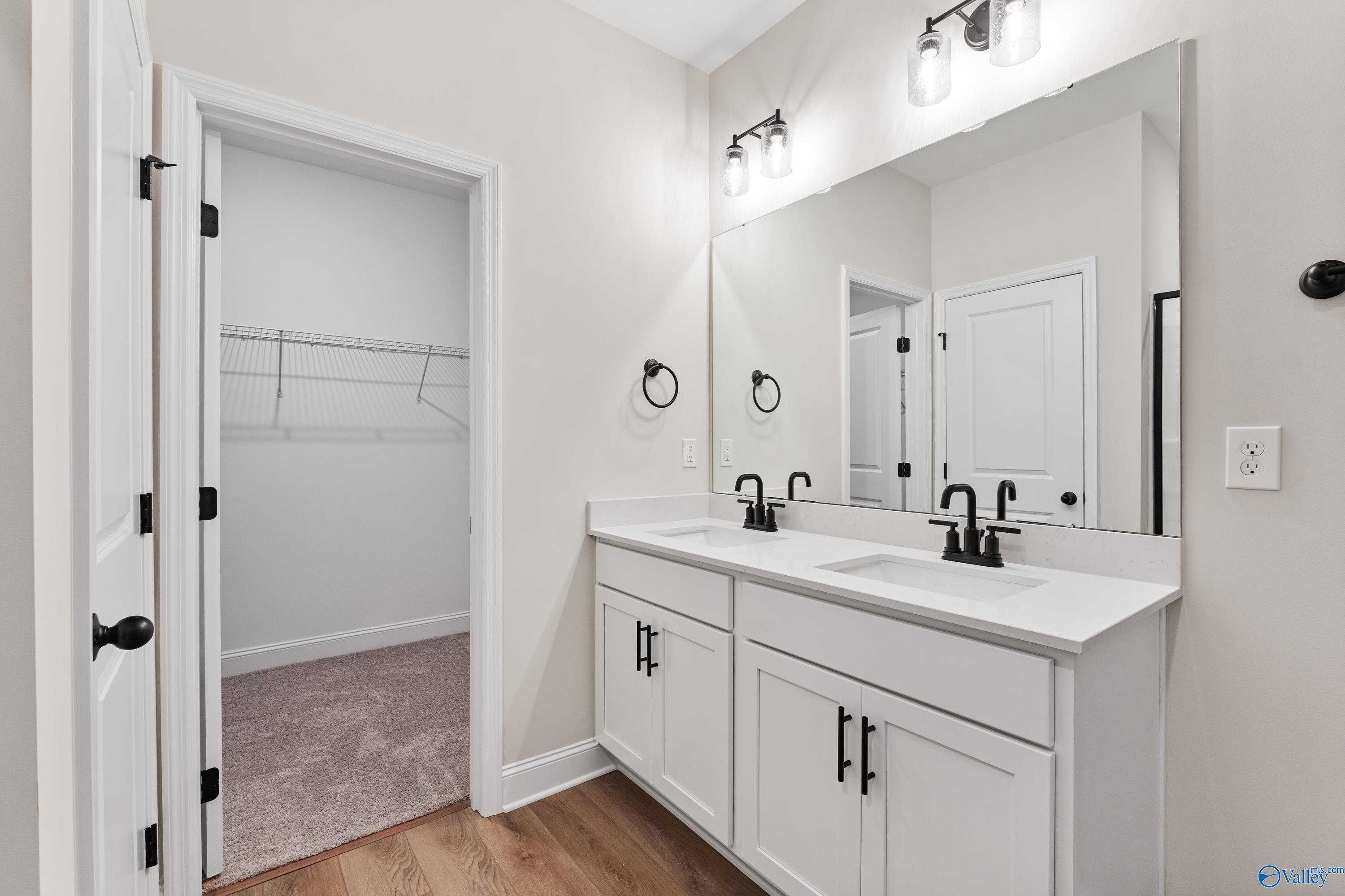 Modern master bathroom featuring double vanity, large mirror, and open walk-in closet in Davidson Homes The Franklin B, Hazel Green, Alabama