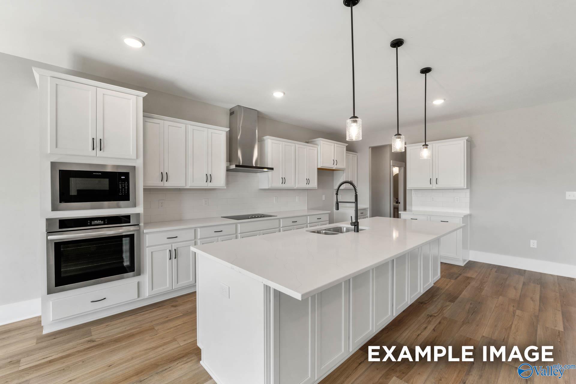 Modern white kitchen with quartz island and stainless appliances in The Finleigh floor plan at Briercreek, Meridianville.