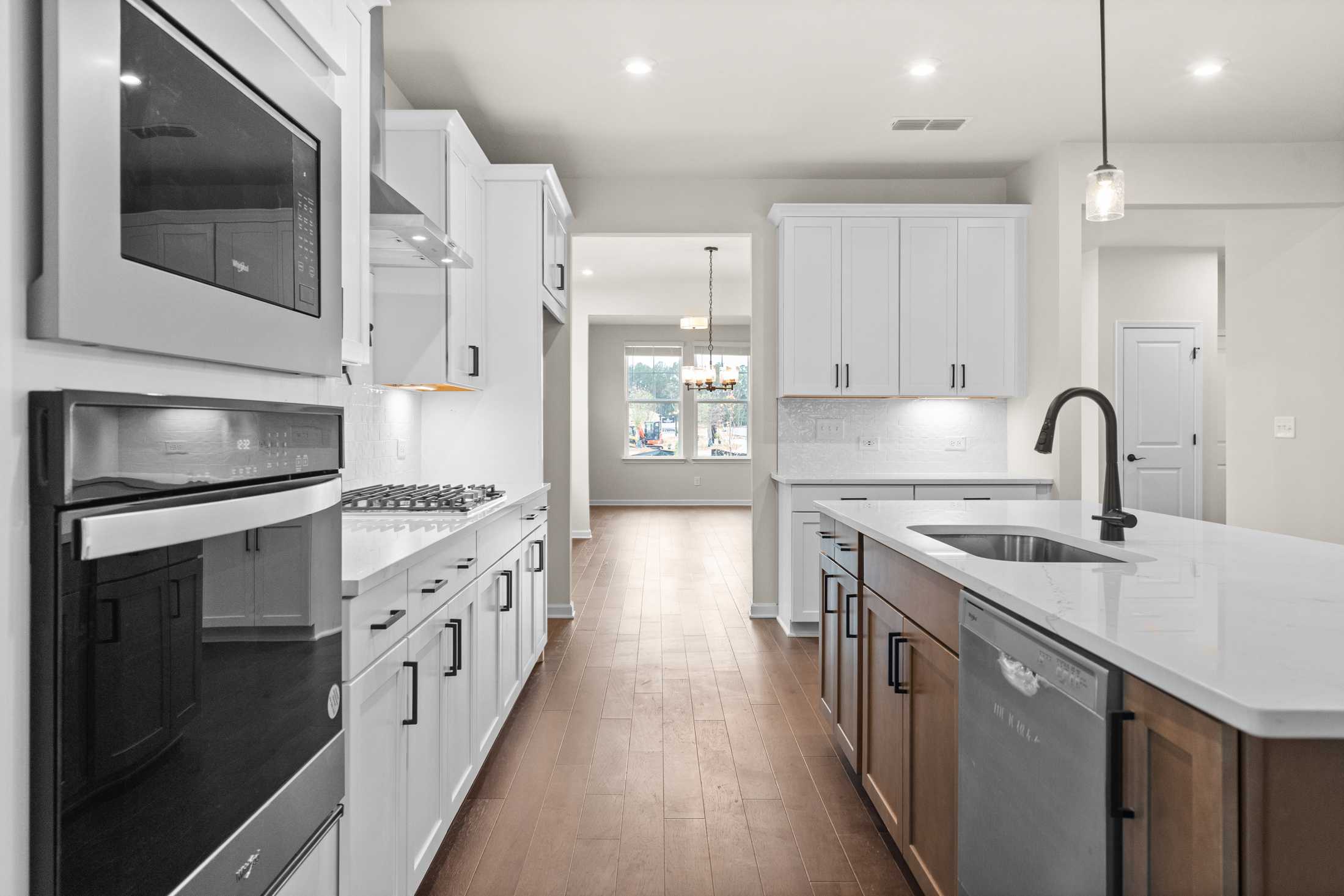 Spacious galley kitchen in The Glenwood B with white shaker cabinets, quartz counters, stainless appliances, and central island