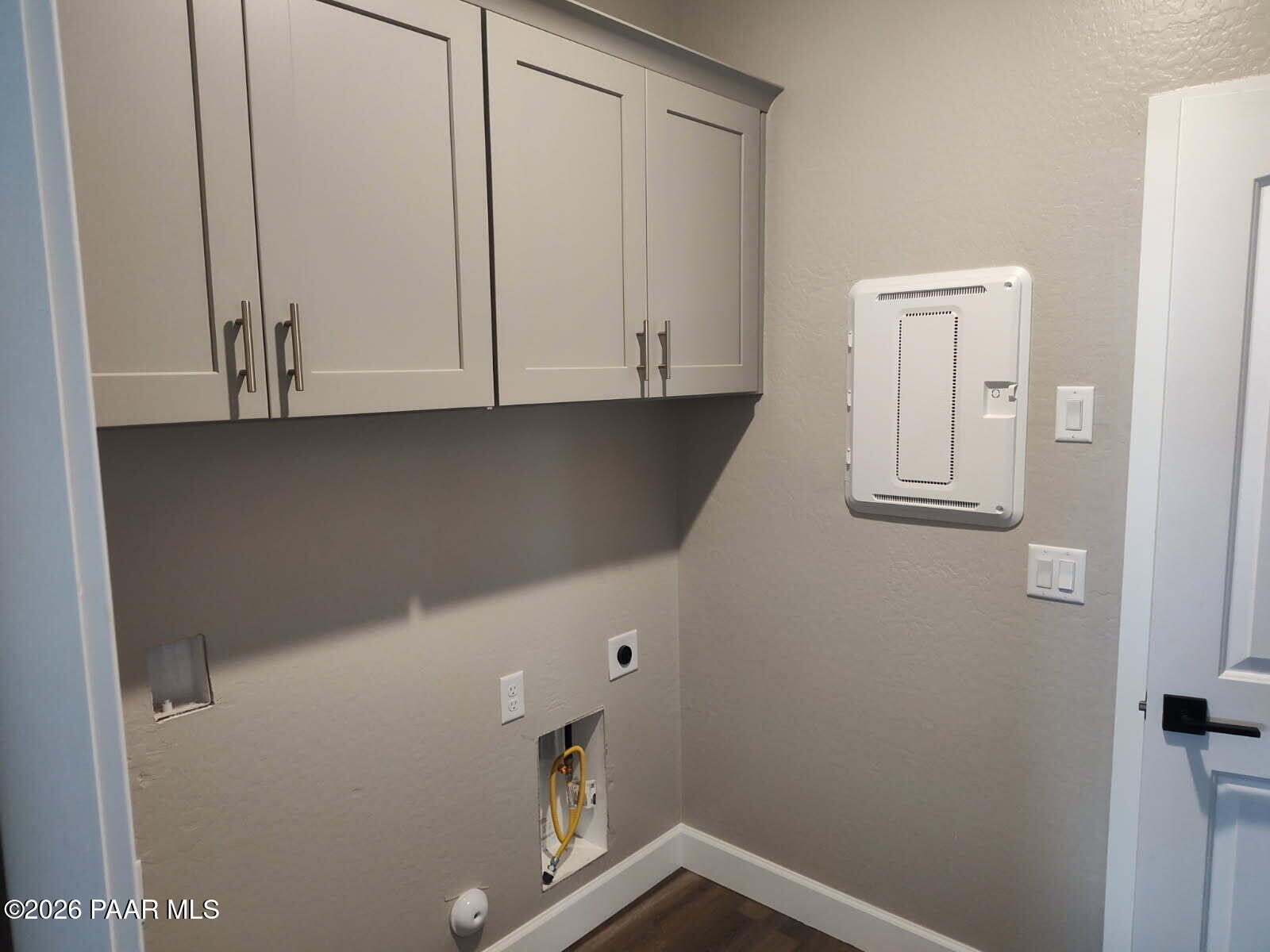 Modern laundry room with gray upper cabinets, utility sink, electrical panel in Davidson Homes The Harmony C, Prescott Valley, AZ