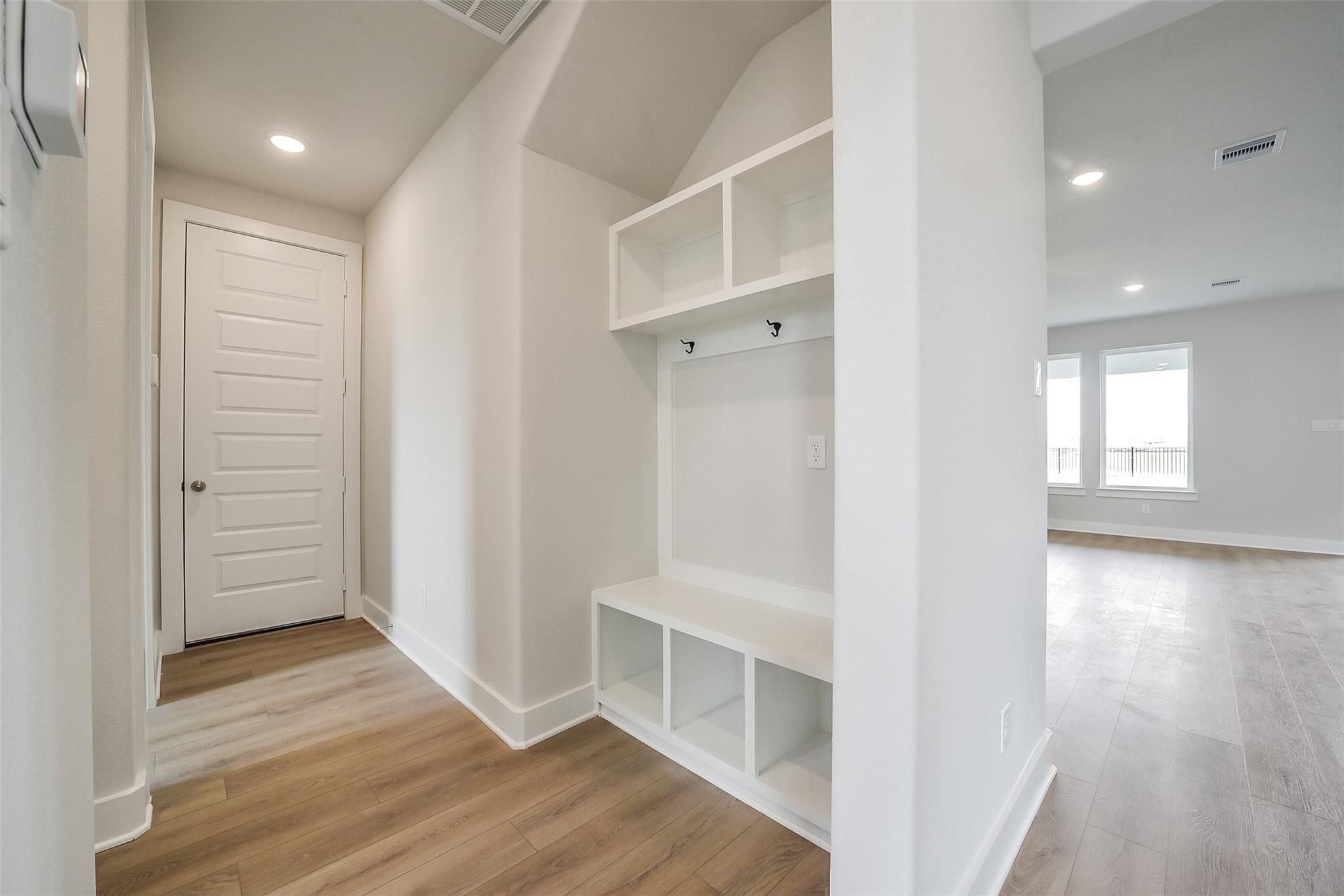 White mudroom with built-in bench, cubbies, and hooks in Davidson Homes The Philip B, 4-bedroom Rosharon, Texas home