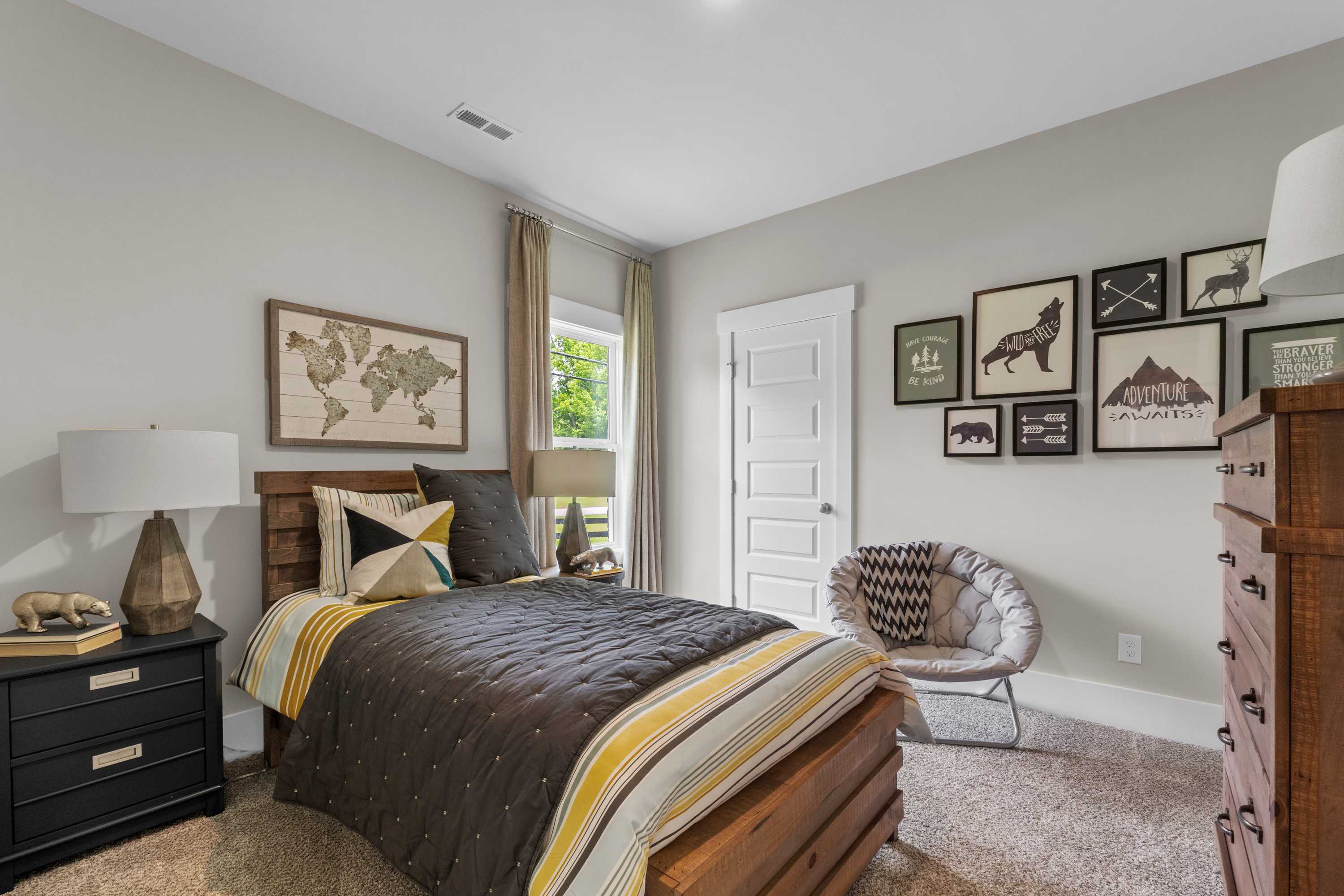 Cozy bedroom in The Highlands Arab Alabama with gray walls, world map art, wooden bed frame, and striped duvet