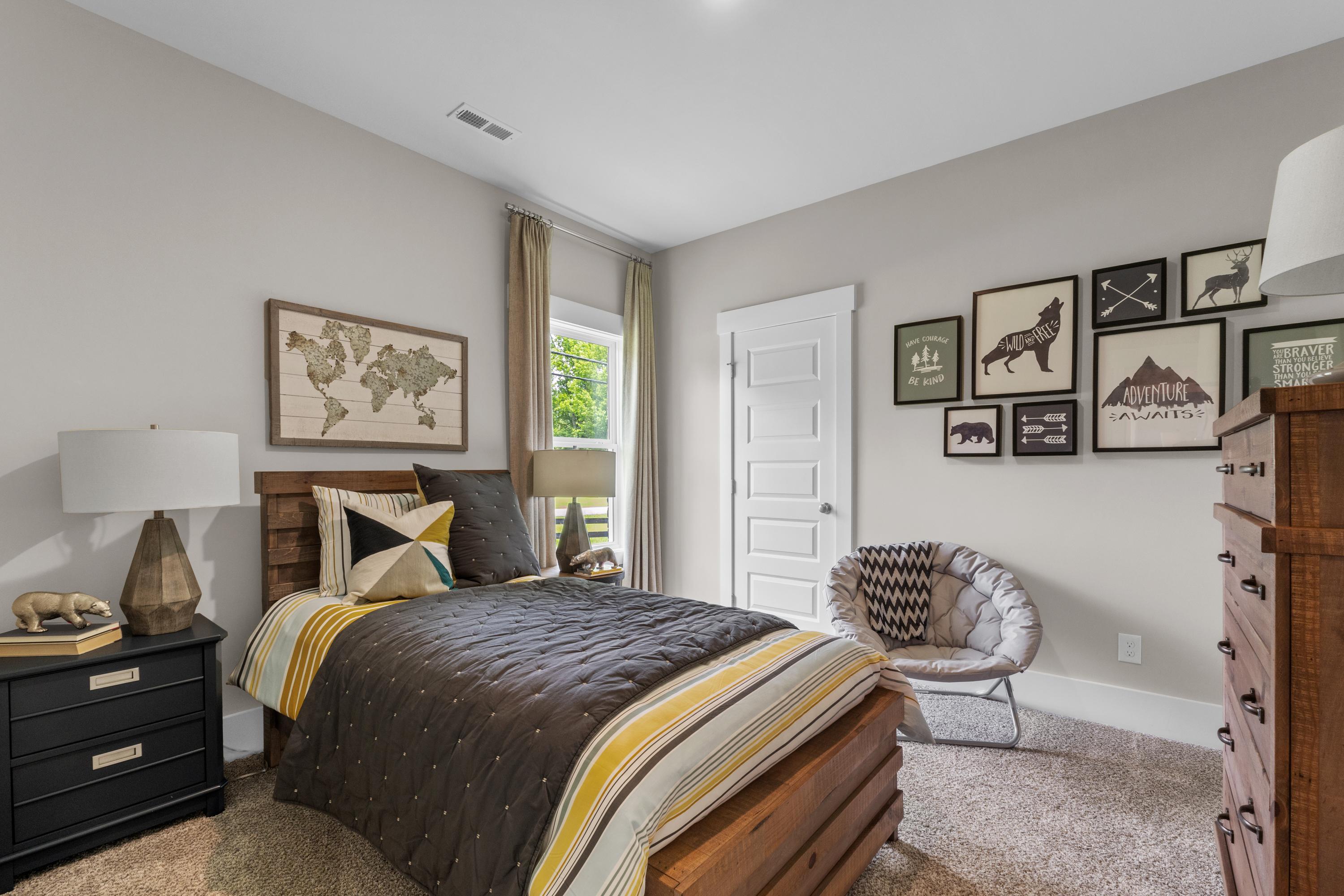 Cozy bedroom in The Highlands Arab Alabama with gray walls, world map art, wooden bed frame, and striped duvet