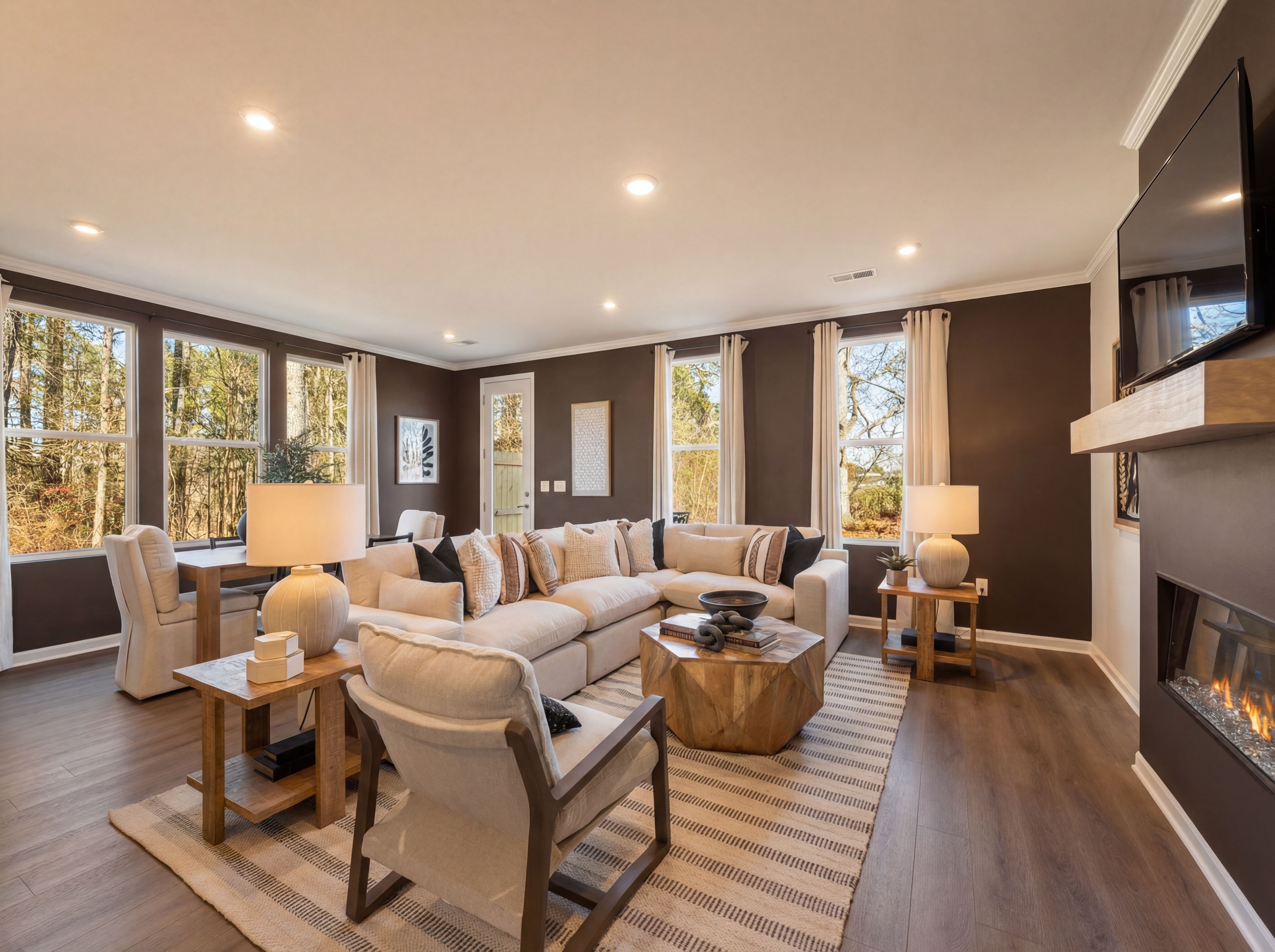 Spacious living room at Lake Shore in Winder GA with white sectional sofa, wood coffee table, fireplace, and large windows