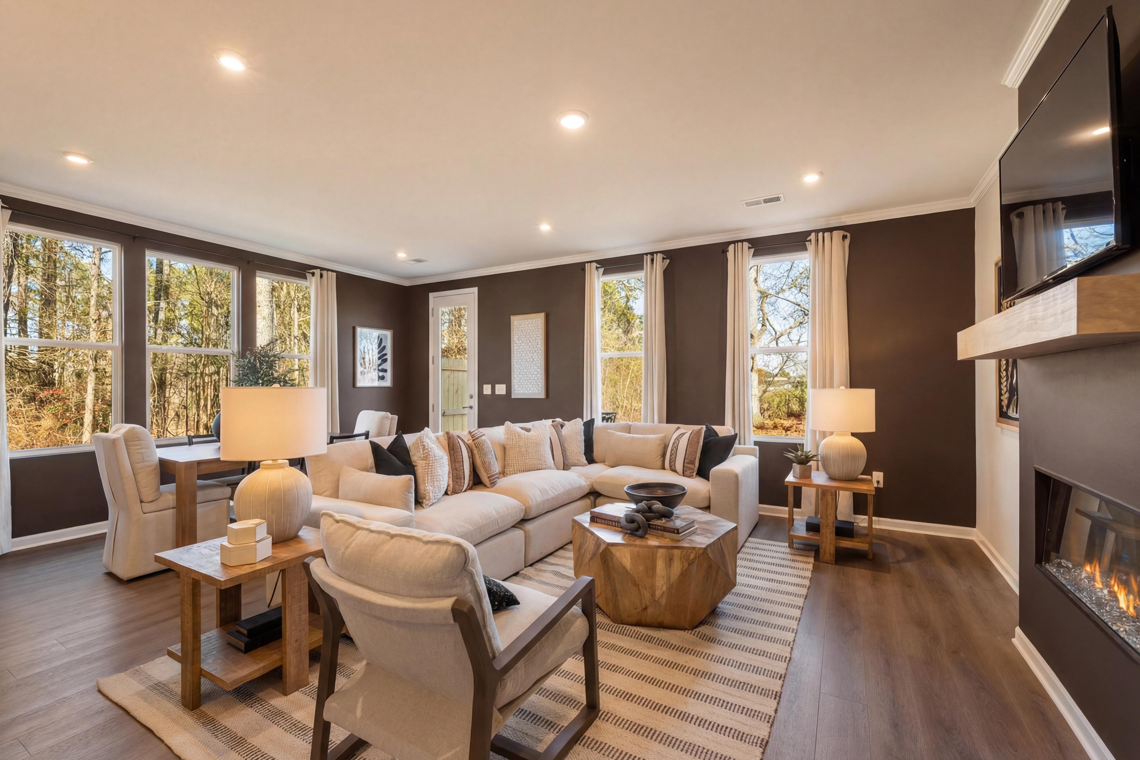 Spacious living room at Lake Shore in Winder GA with white sectional sofa, wood coffee table, fireplace, and large windows