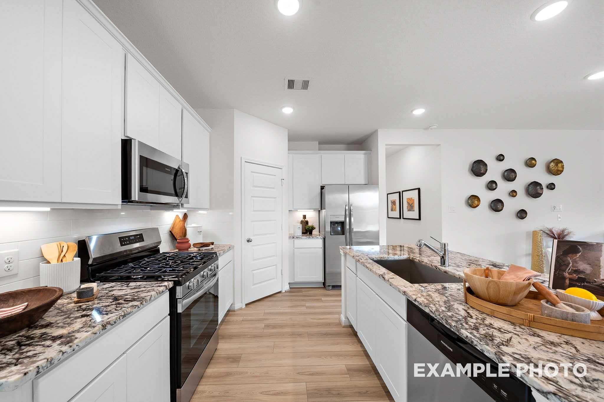Modern kitchen with white shaker cabinets, granite countertops, stainless appliances, and island sink in Davidson Homes Sabine E plan, Conroe