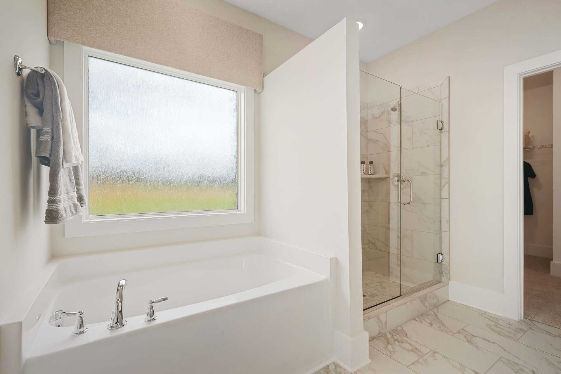 Spacious bathroom in Flint Meadows, New Market AL with freestanding tub, glass shower, frosted window and neutral tones