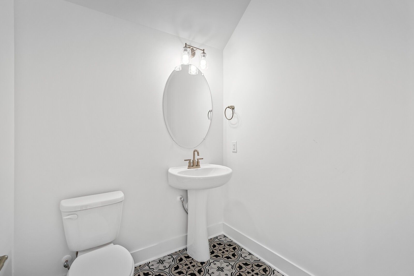 Modern powder room featuring pedestal sink, round mirror, and geometric tile floor in Davidson Homes The Logan C, Gallatin, Tennessee
