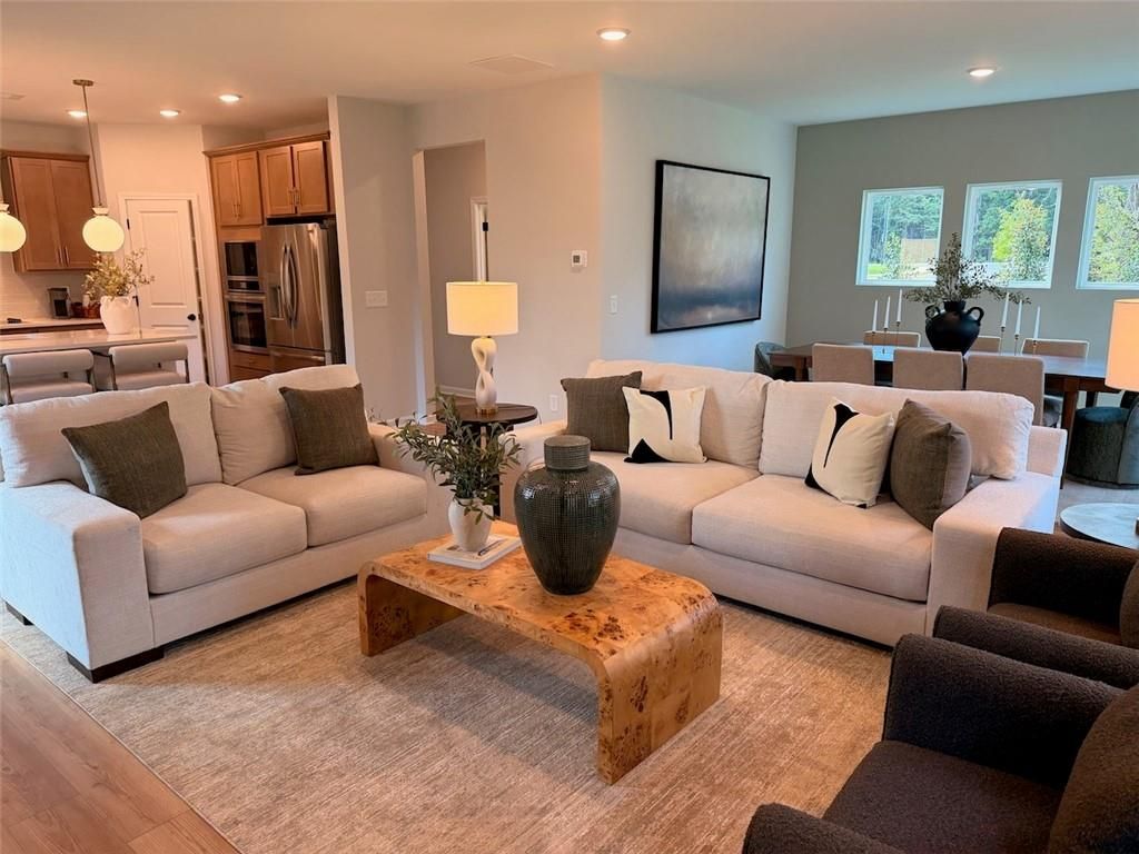 Open-concept living room with cream sofas and burl wood coffee table in Davidson Homes Pinecrest J, Cartersville, GA