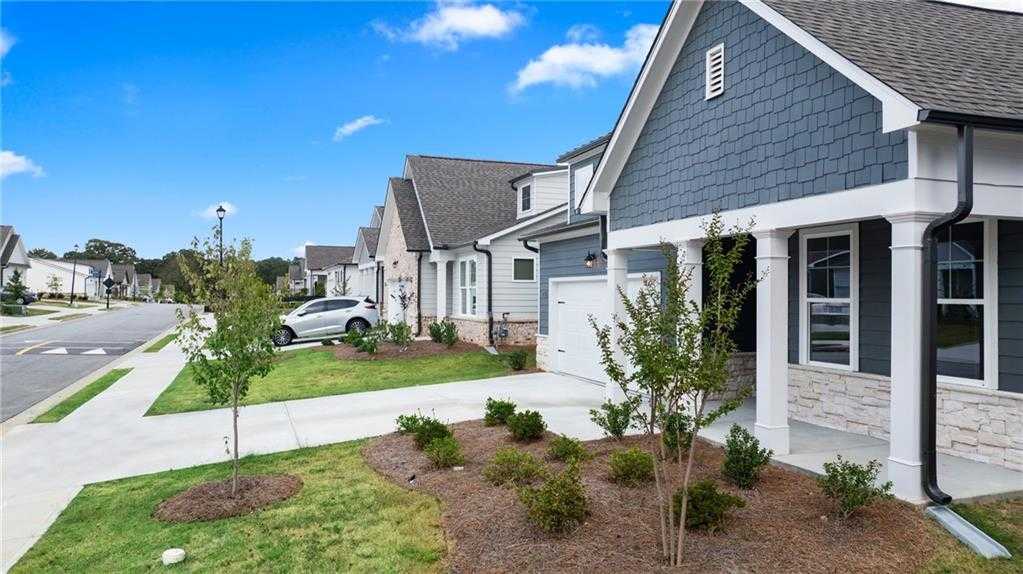 Modern 3-bedroom single-story home with blue-gray siding, columned porch, 2-car garage in Kelly Preserve, Loganville, GA by Davidson Homes