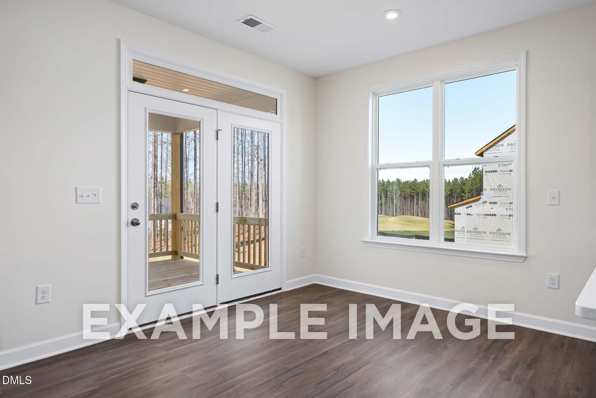 Bright bedroom with French doors to deck overlooking pines and large window in Davidson Homes The Ash B, Zebulon, NC