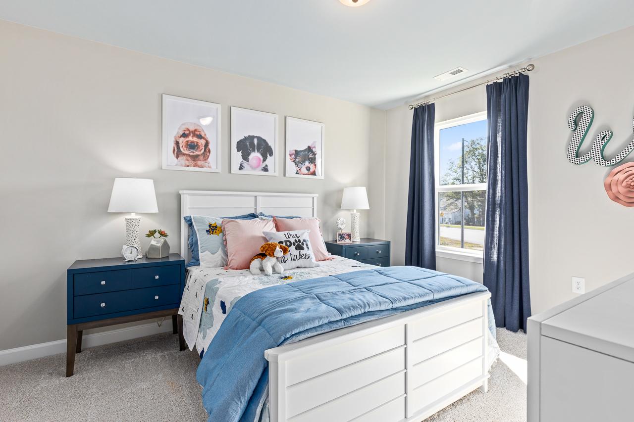 Cozy secondary bedroom in The Hemlock featuring a white bed frame, blue nightstands, and playful puppy-themed wall art.
