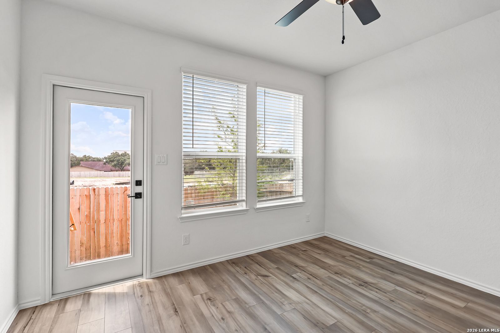 Bright bedroom with wood-look flooring and backyard access in The Gillian C floor plan at Meadows at Oak Creek, San Antonio.
