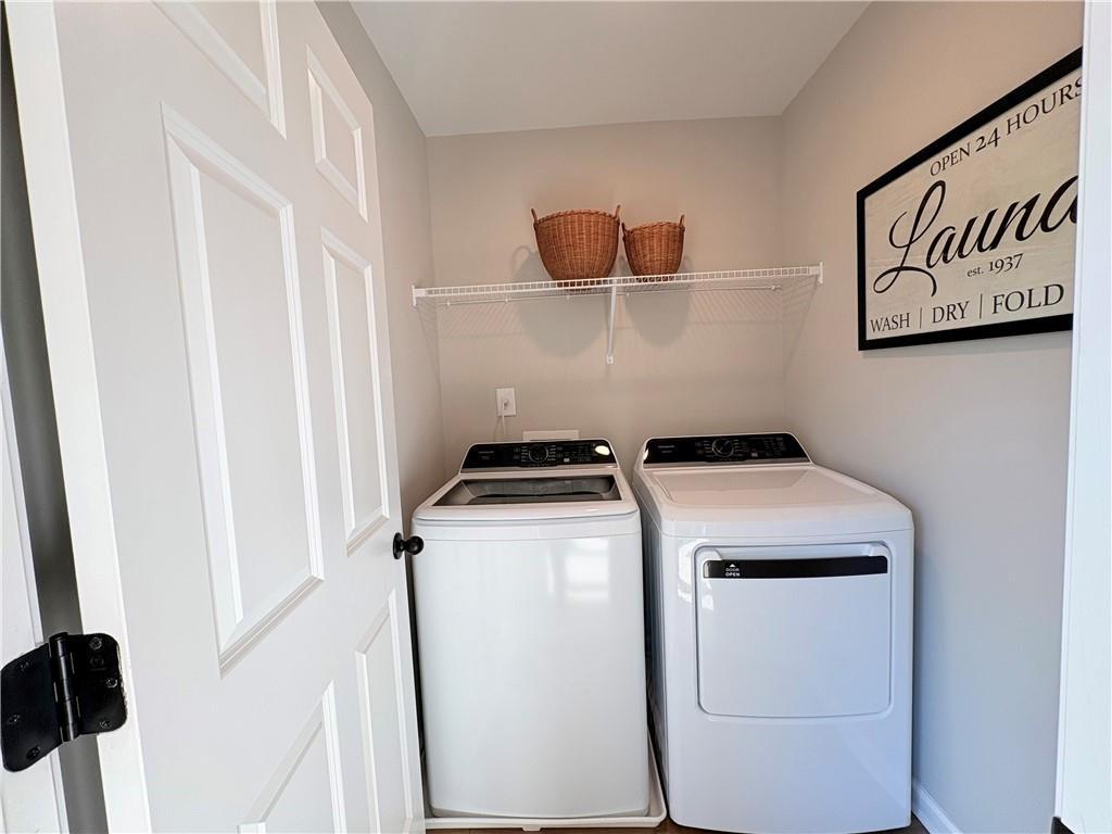 White washer and dryer in spacious laundry room with shelves, baskets, and sign in The Durham D home, Cumming, Georgia