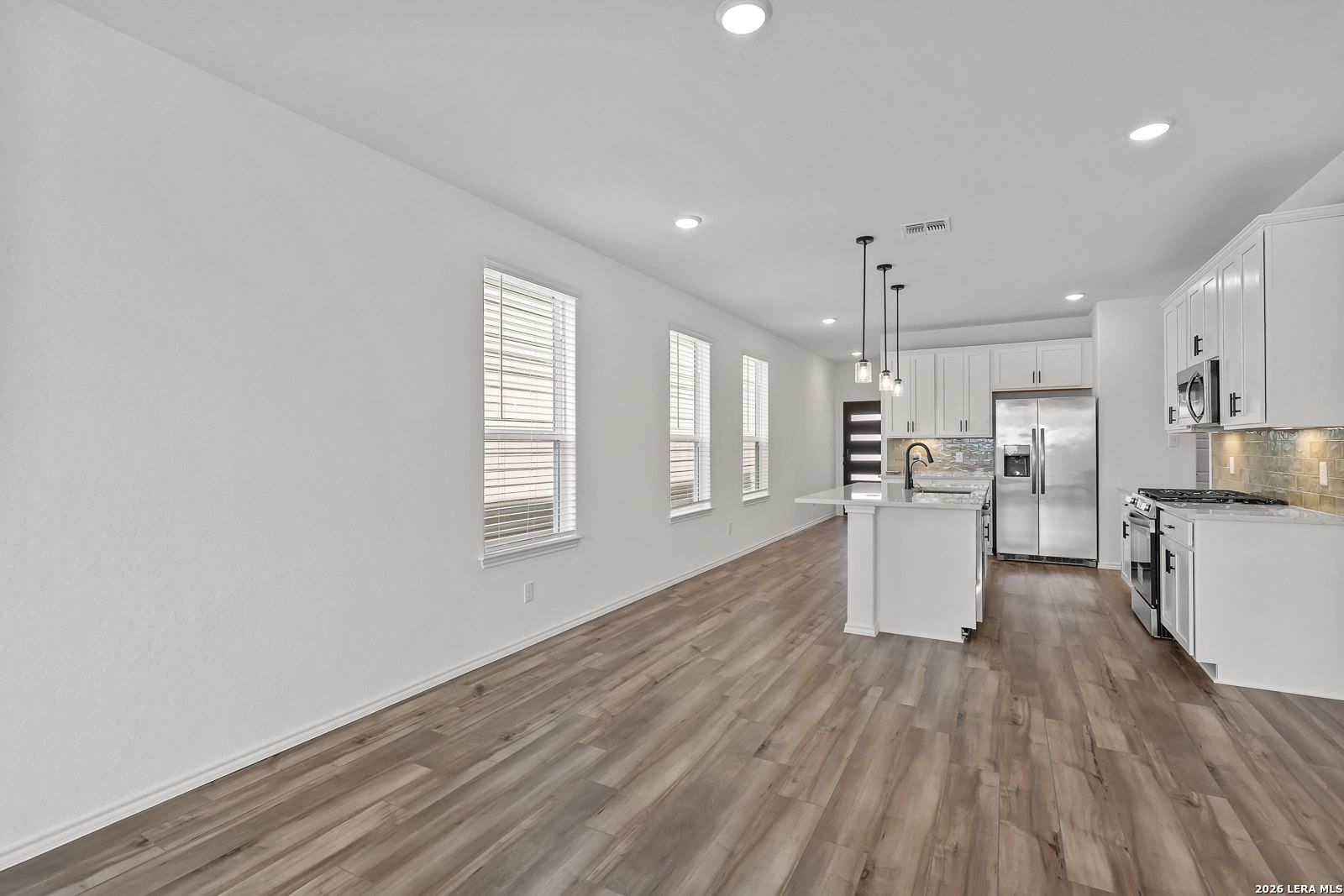 Modern white kitchen with island and stainless steel appliances in The Gillian C floor plan at Meadows at Oak Creek, SA.