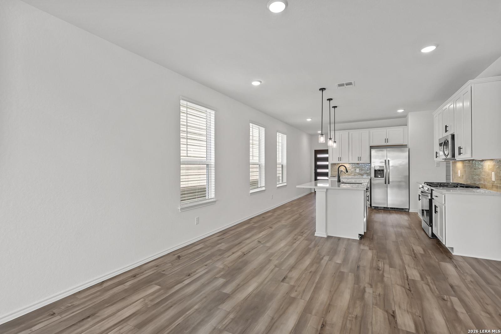 Modern white kitchen with island and stainless steel appliances in The Gillian C floor plan at Meadows at Oak Creek, SA.