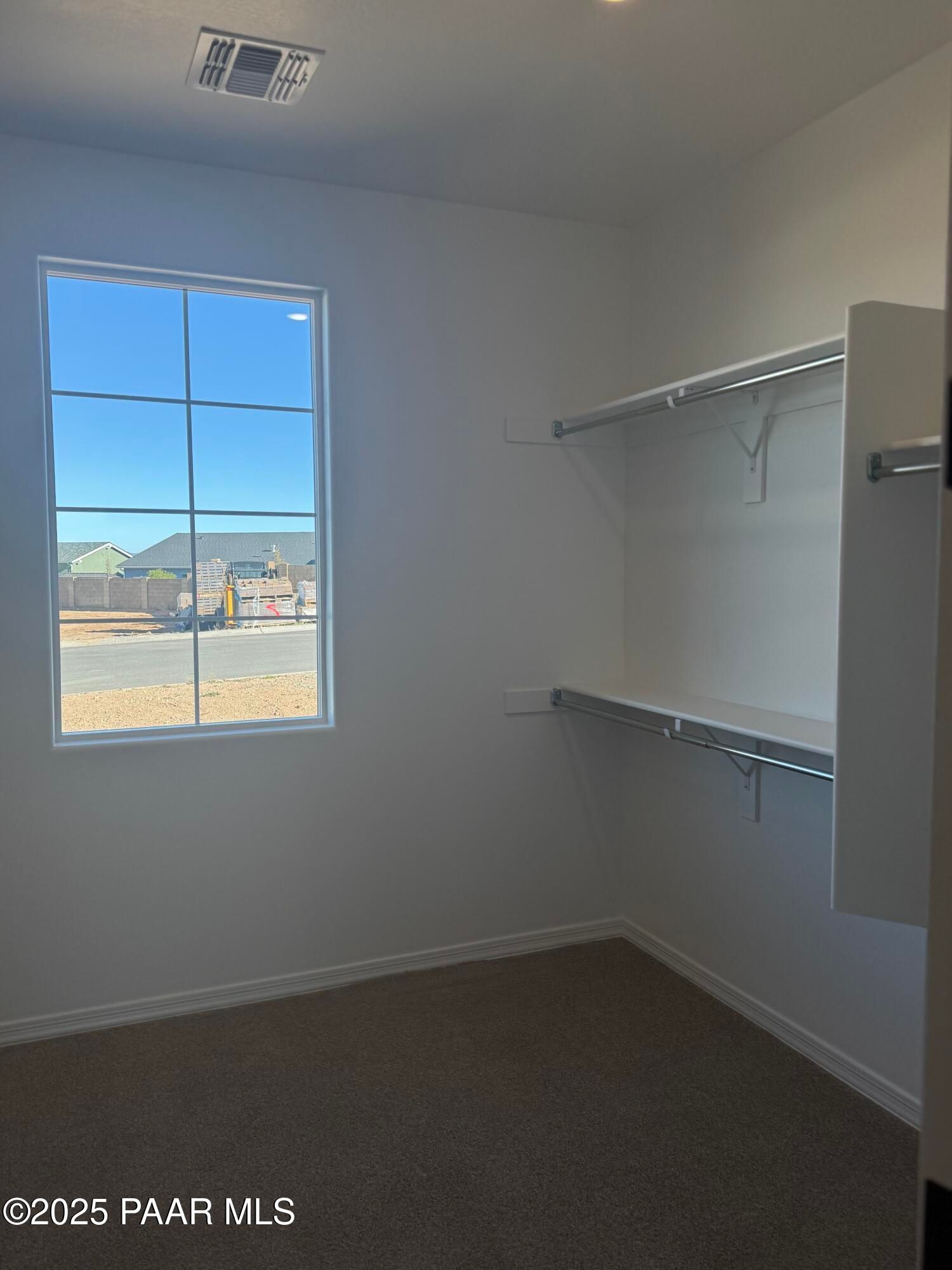 Spacious walk-in closet with built-in shelving, hanging rods, and large sunny window in Davidson Homes The Monarch E, Prescott, AZ