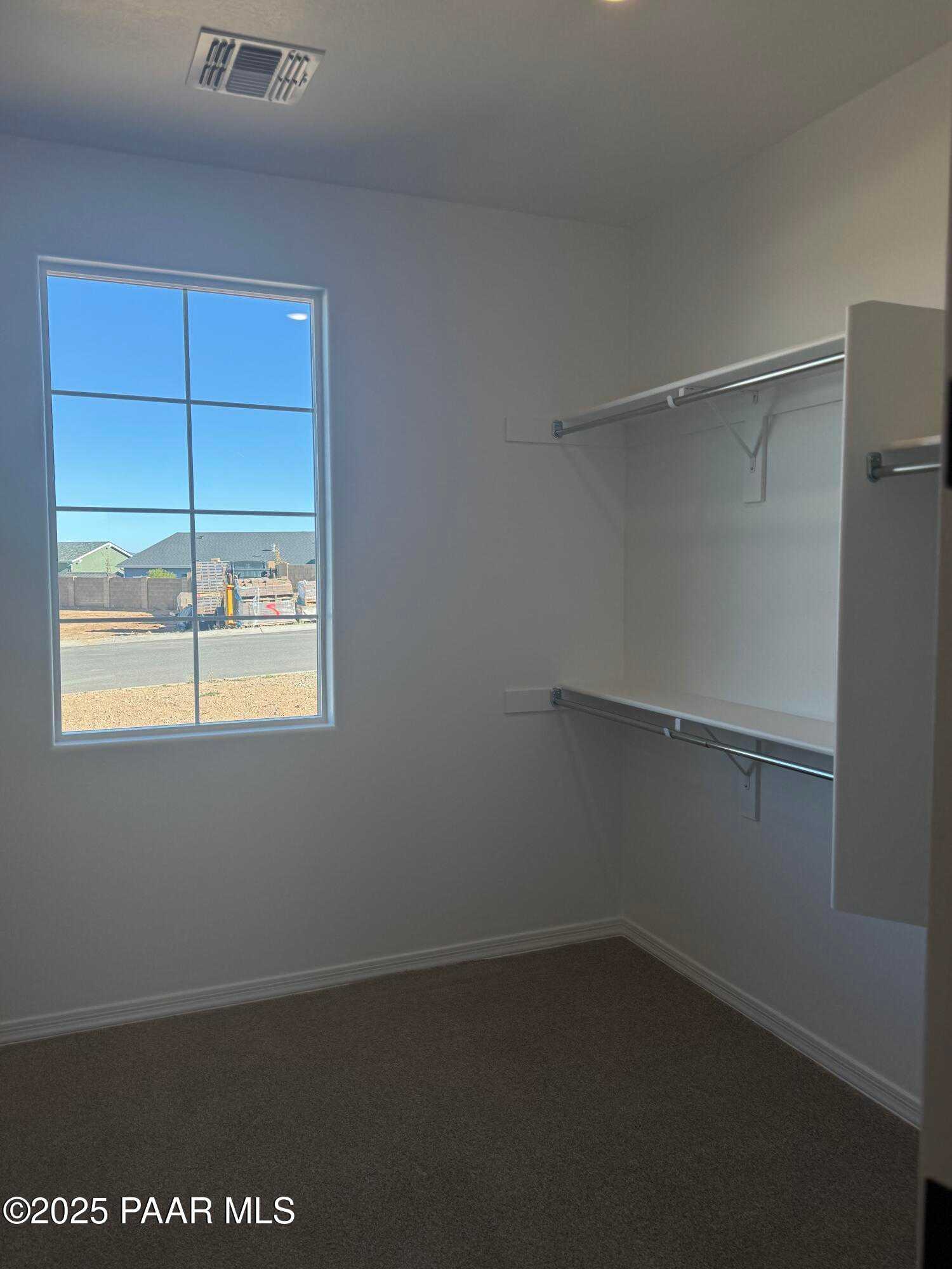Spacious walk-in closet with built-in shelving, hanging rods, and large sunny window in Davidson Homes The Monarch E, Prescott, AZ