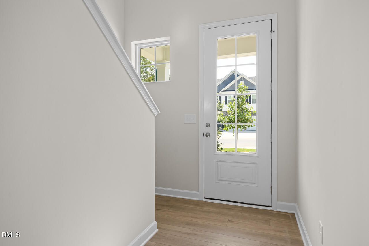Bright entryway with white door and hardwood floors in The Gavin A floor plan by Davidson Homes in Gregory Village, NC.