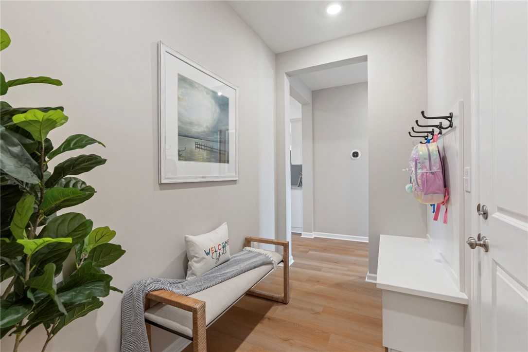 Modern entryway with cushioned bench, coat hooks holding backpacks, fiddle leaf plant and hallway in Davidson Homes The Phoenix B, Opelika Alabama