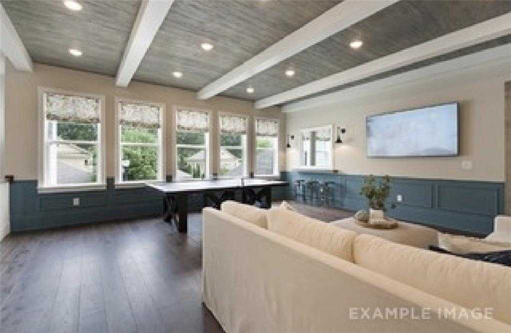 Spacious family room with vaulted beamed ceiling, game table, white sofa, large windows in Davidson Homes The Seaside A, Woodstock GA