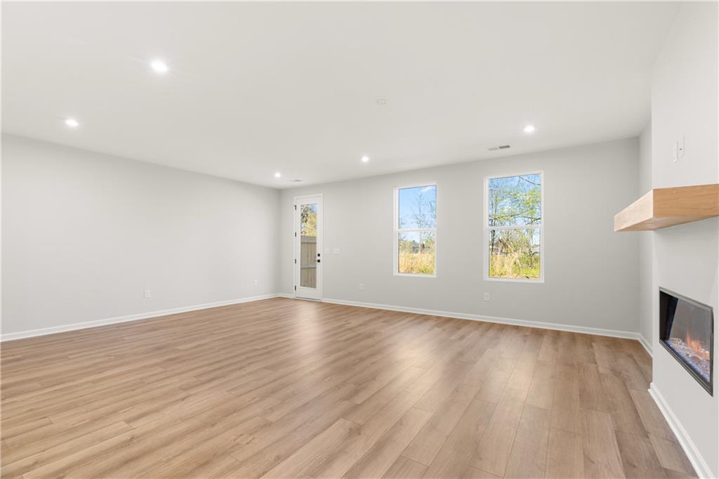 Bright living room with gas fireplace, hardwood floors, and large windows in Davidson Homes The Cary A, Winder, Georgia