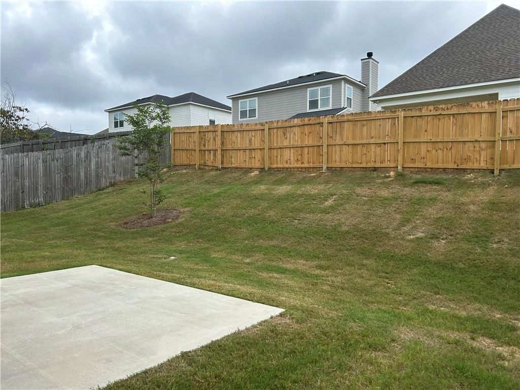 Sloped grassy backyard with concrete patio slab and wooden privacy fence in Davidson Homes The Bartlett, Summer Vineyard, Phenix City, Alabama