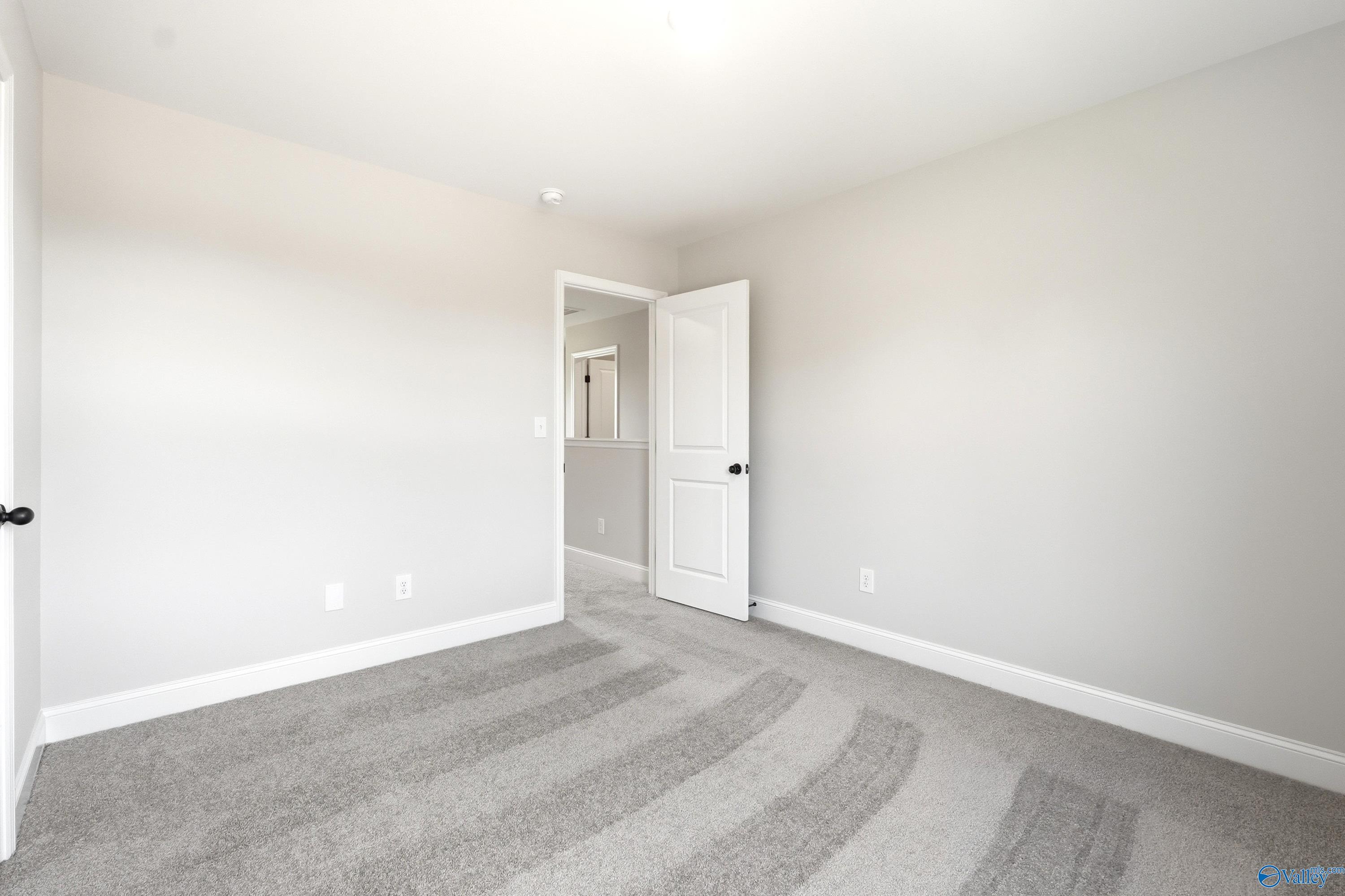 Bright, neutral-toned secondary bedroom with plush carpet in The Russell A floor plan by Davidson Homes in Huntsville, AL.