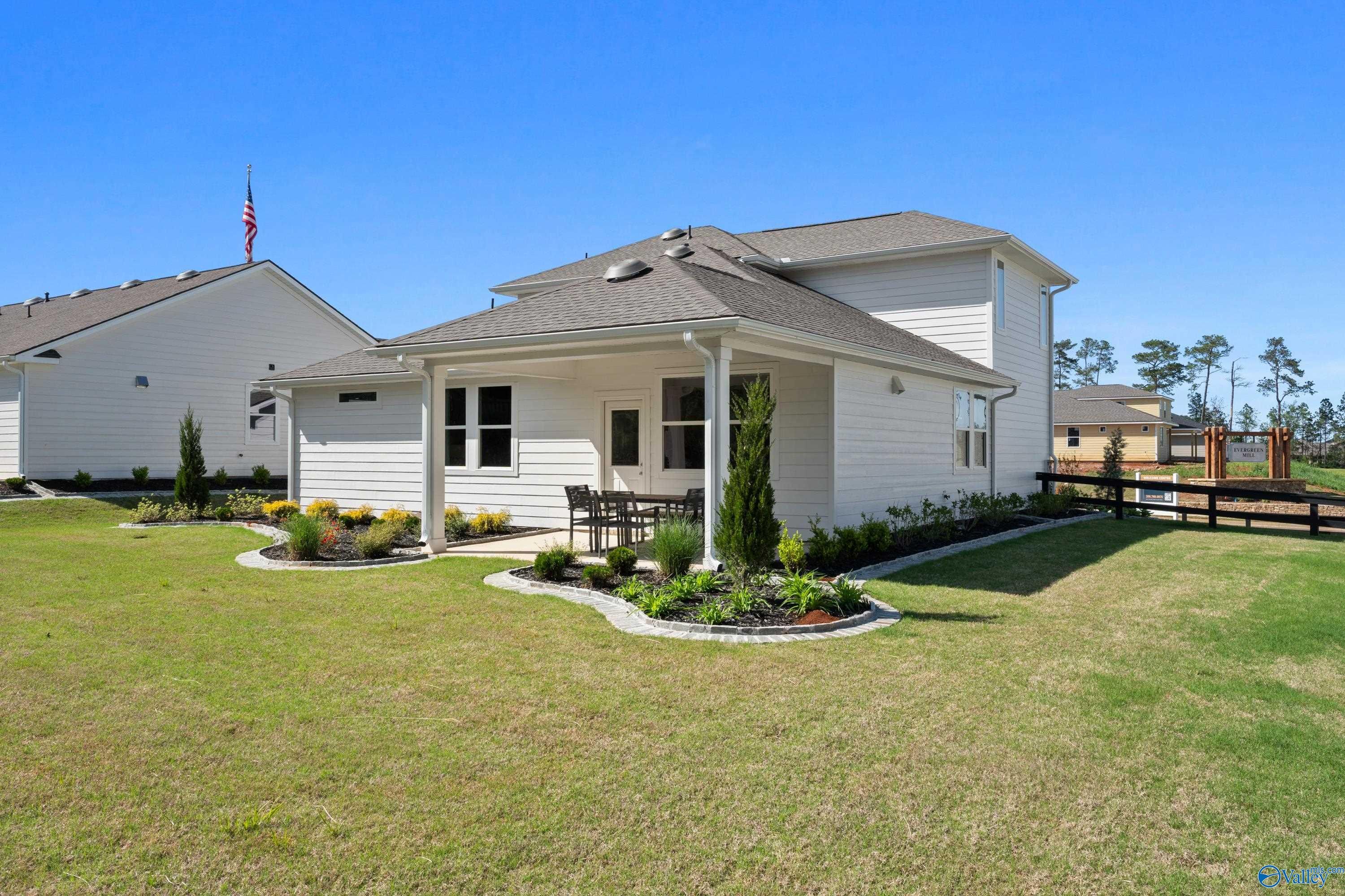 Covered back patio with seating and curved landscaped yard in Davidson Homes The Stella, Evergreen Mill, Madison, Alabama