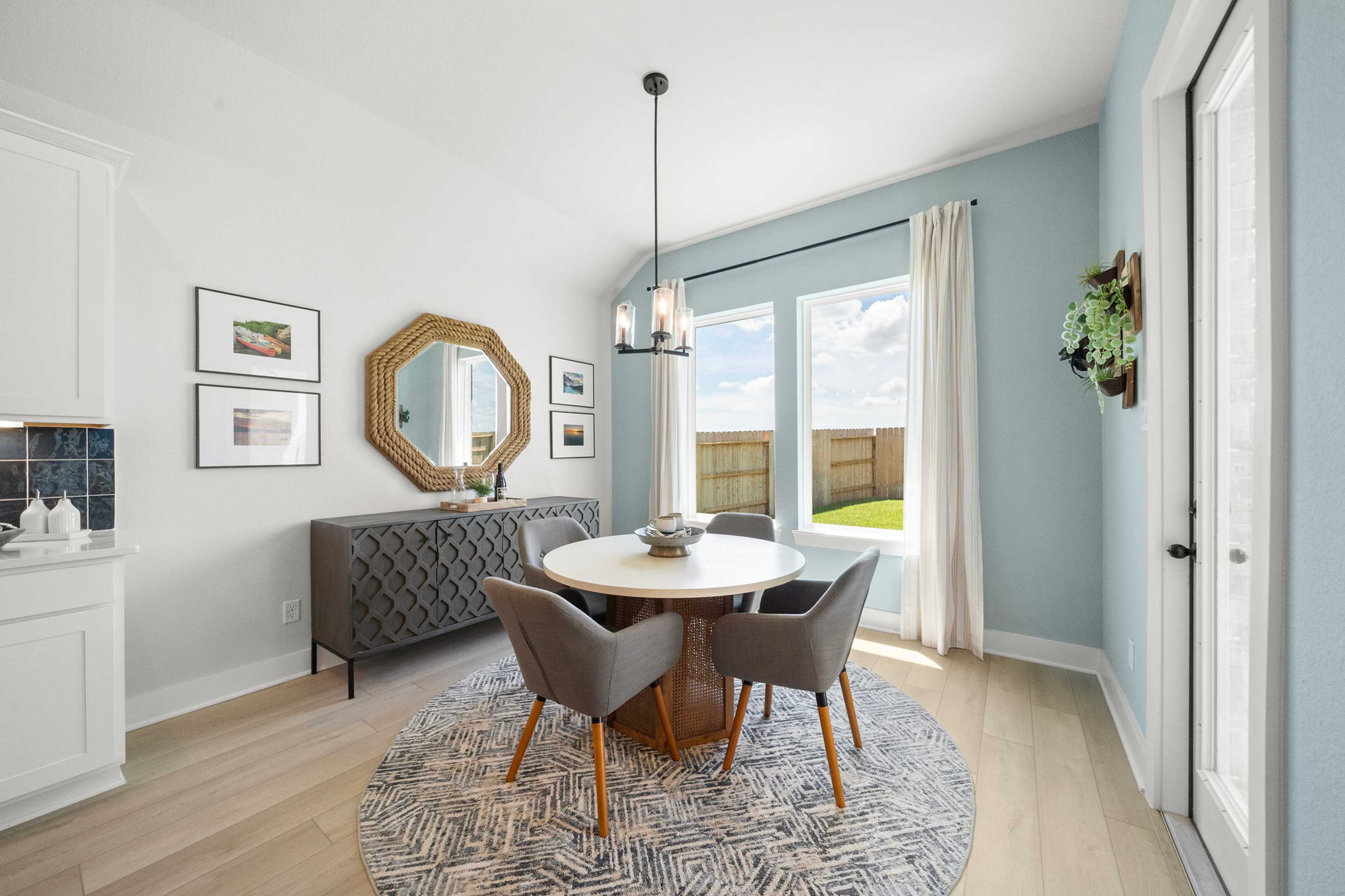 Modern dining room at Lago Mar in Texas City TX by Davidson Homes with round table, chandelier, and backyard view windows