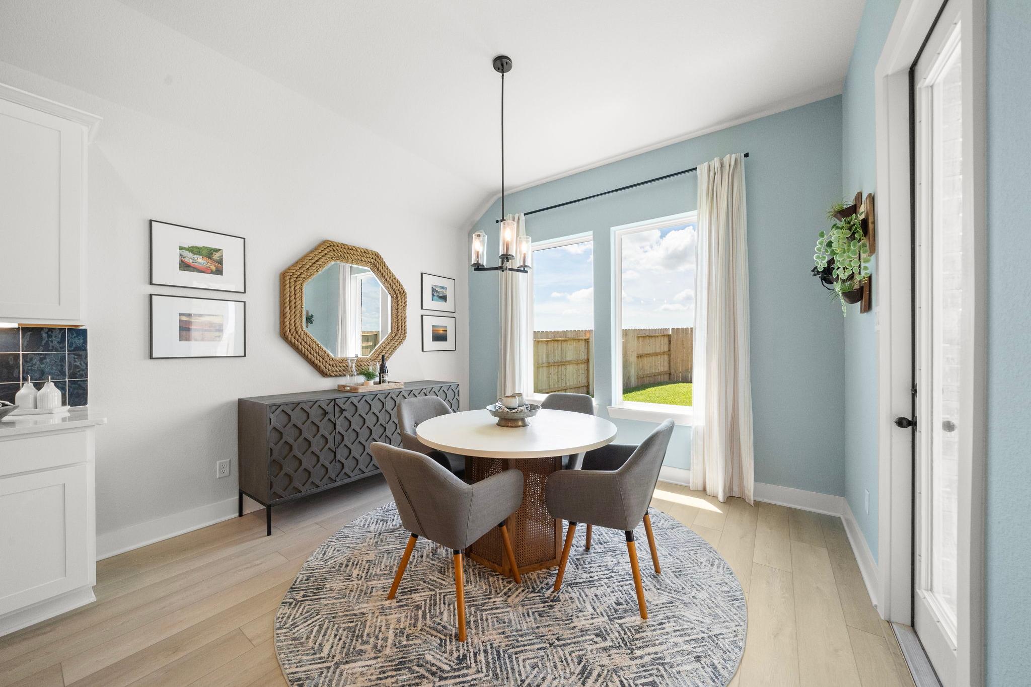 Modern dining room at Lago Mar in Texas City TX by Davidson Homes with round table, chandelier, and backyard view windows