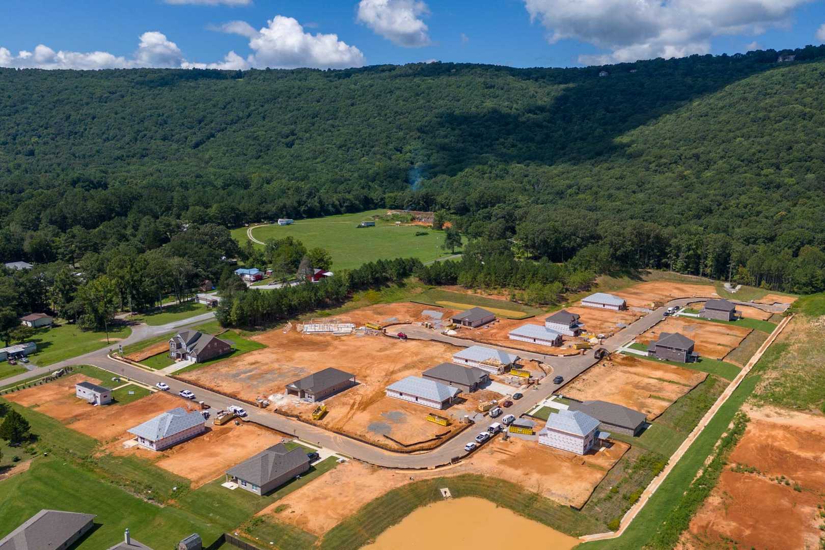 Aerial view of new homes under construction at Watts Glen in Owens Cross Roads, Alabama amid wooded hills and fields