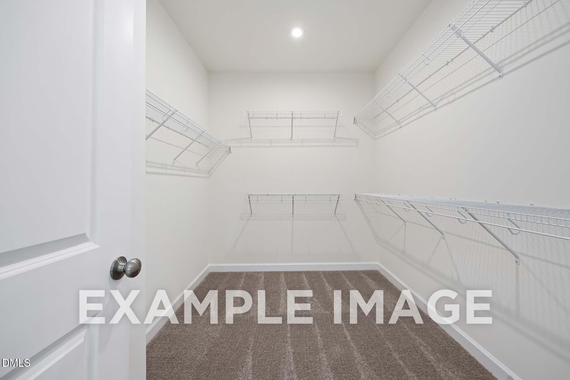 Spacious walk-in closet with white wire shelving and carpeted floor in The Ash B master suite, Davidson Homes, Zebulon, NC
