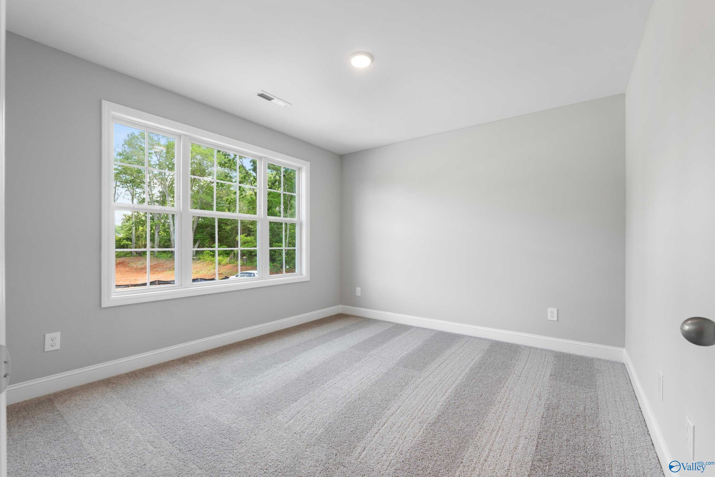 Bright secondary bedroom with large window overlooking trees, gray carpet and walls in Davidson Homes Chelsea B, New Market AL