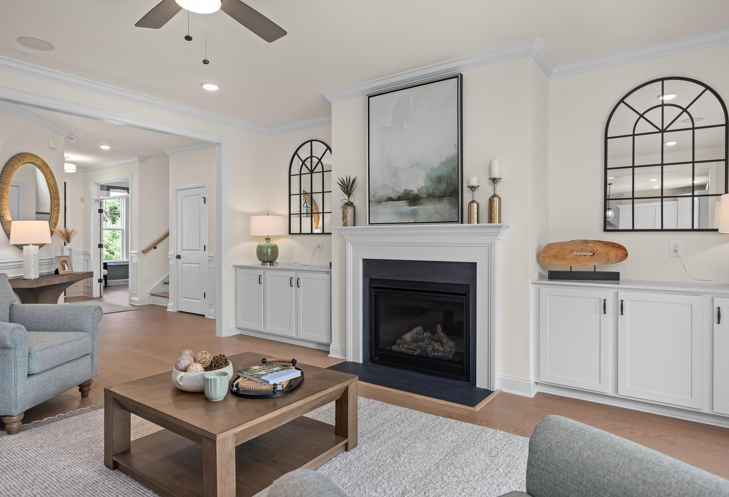 Cozy living room in The Crawford by Davidson Homes featuring gas fireplace, arched mirrors, abstract art, and open layout