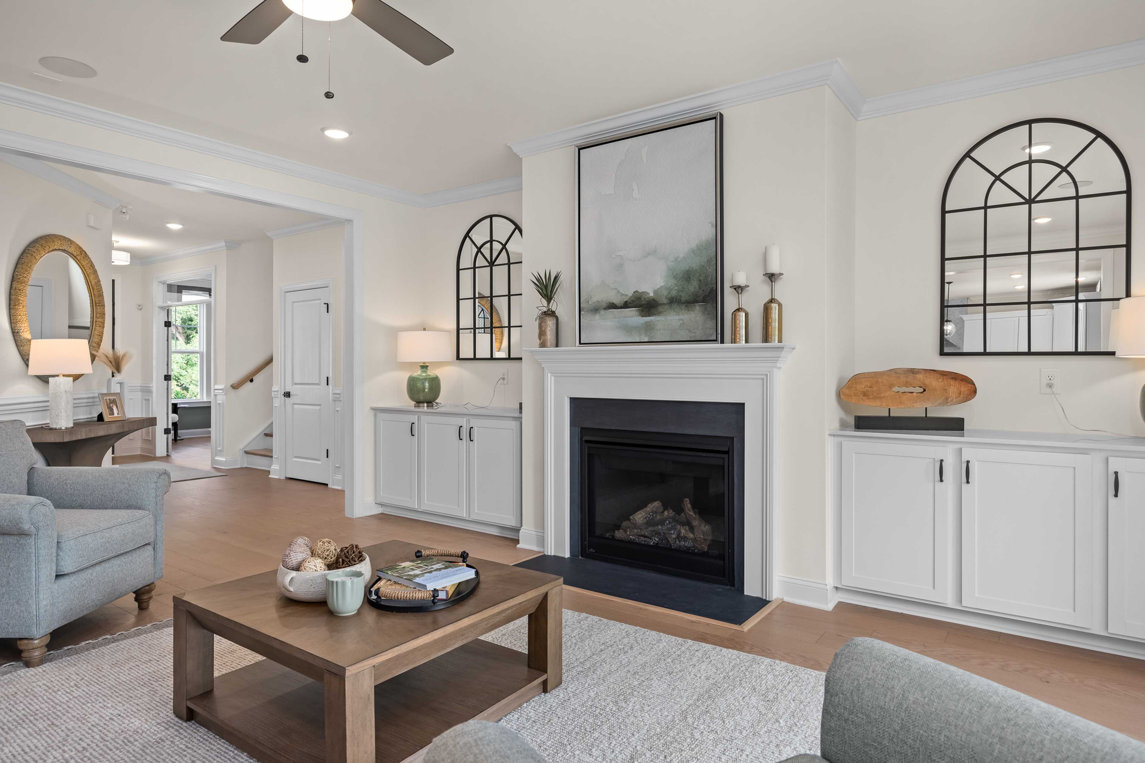 Spacious open-concept living room at Laneridge Estates in Raleigh NC with gas fireplace, hardwood floors, arched windows, and modern decor