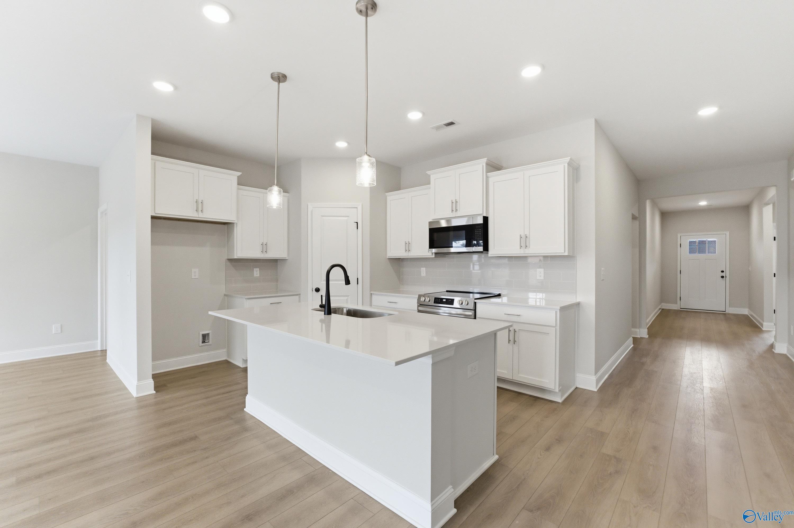 Modern white kitchen island with quartz counters, stainless appliances in Davidson Homes The Daphne C, Huntsville, AL