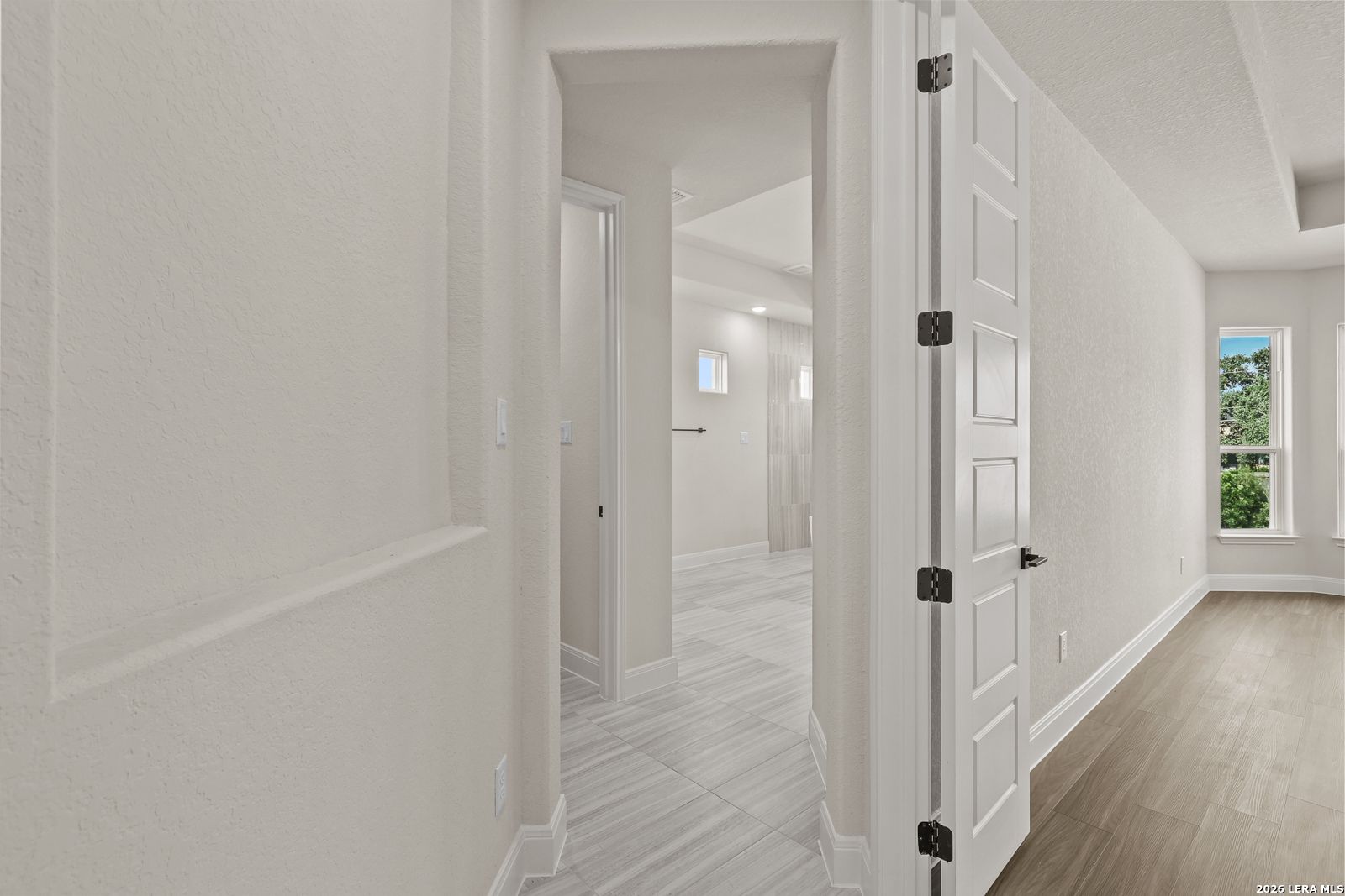 Bright hallway leading to a modern bathroom in The Summerlin B floor plan by Davidson Homes in Potranco Oaks, Castroville.