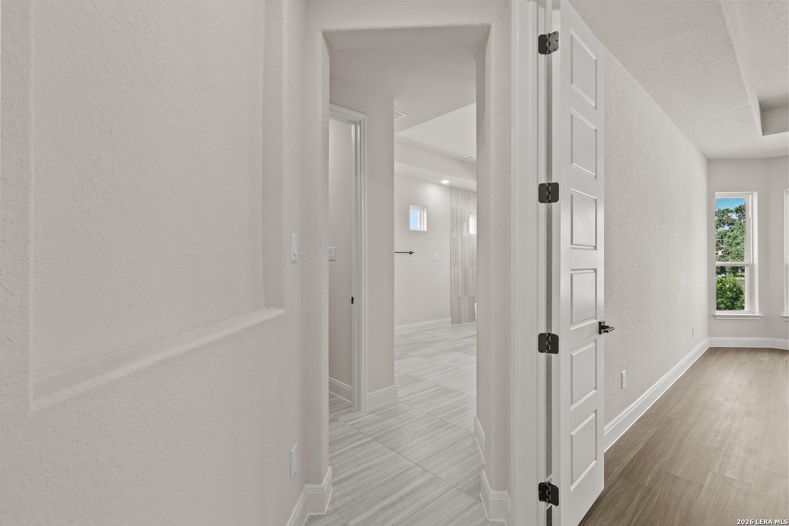 Bright hallway leading to a modern bathroom in The Summerlin B floor plan by Davidson Homes in Potranco Oaks, Castroville.