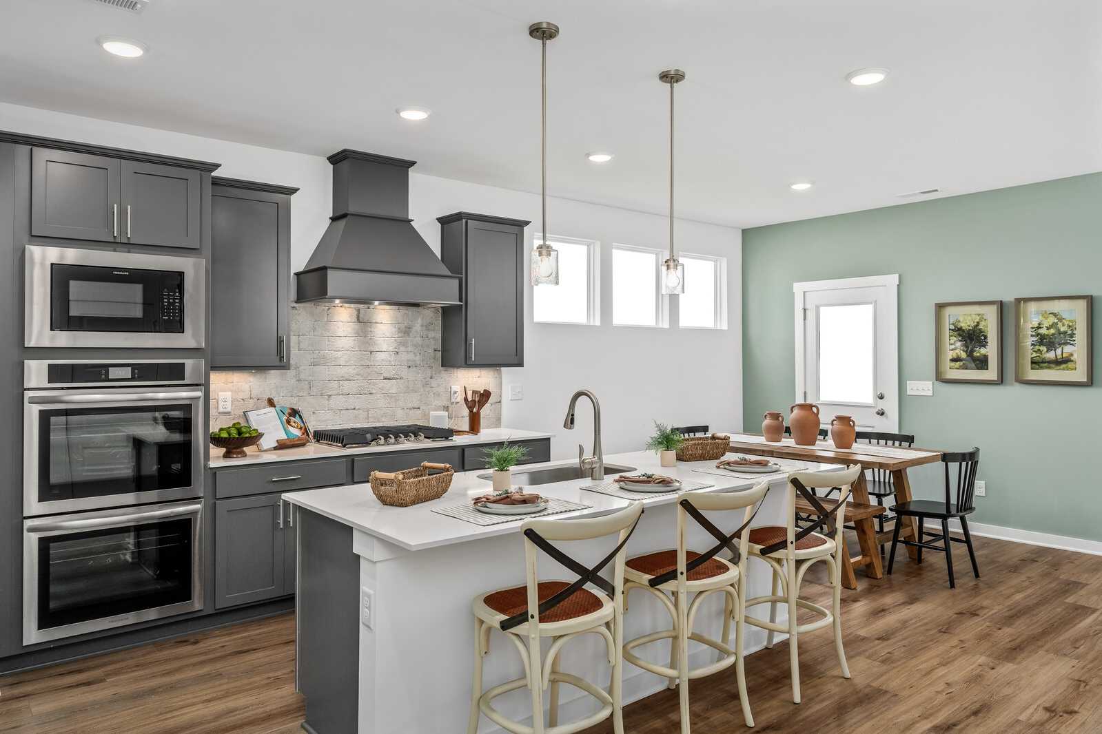 Spacious modern kitchen in Calista Farms White House TN home with gray shaker cabinets, white quartz island, stainless appliances, hardwood floors