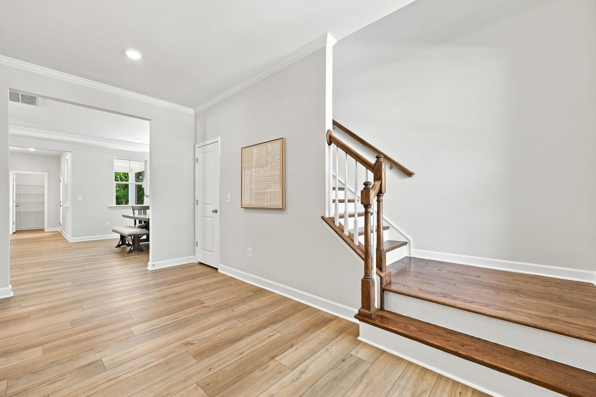 Foyer entrance of The Jordan A in Knightdale, featuring hardwood floors, a staircase, and a view into the dining area.