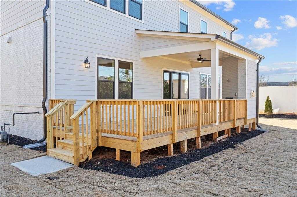 Covered back porch with wooden deck railing, steps, and ceiling fan on white-sided Davidson Homes in East Cobb, Georgia