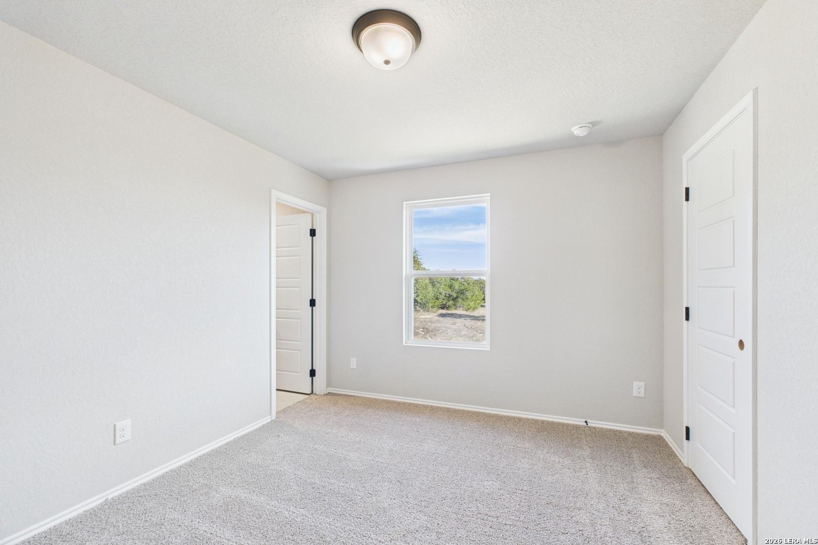 Bright secondary bedroom with beige carpet, ceiling fan light, large window, and double doors in Davidson Homes The Douglas E, San Antonio
