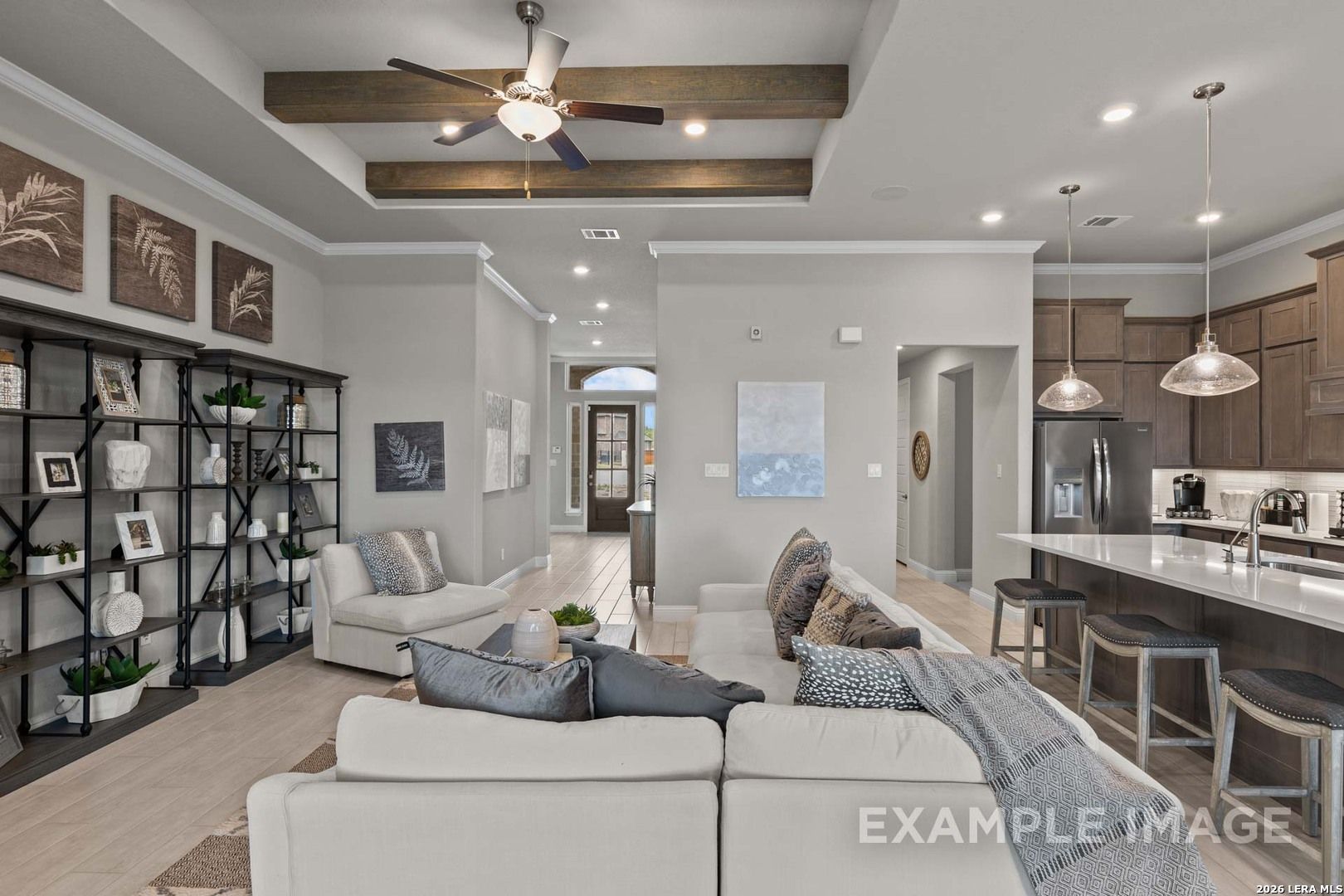 Open-concept living room with wood beam ceiling and kitchen island in The Garner C floor plan, The Reserve at Potranco Oaks.
