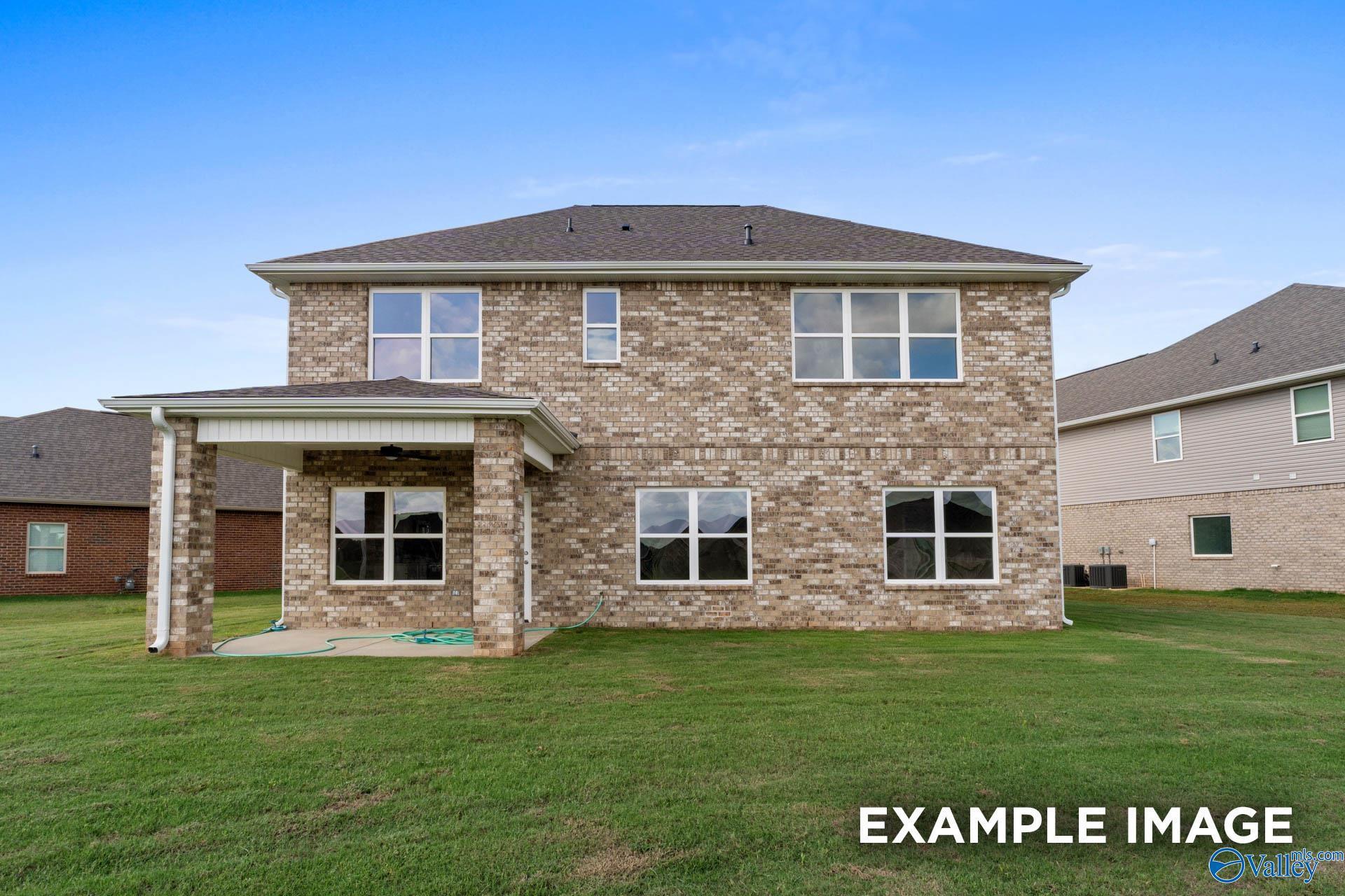 Two-story brick home with covered back patio, large grassy yard, and multiple windows in Heritage Lakes, New Market, Alabama - Shelby B by Davidson Homes